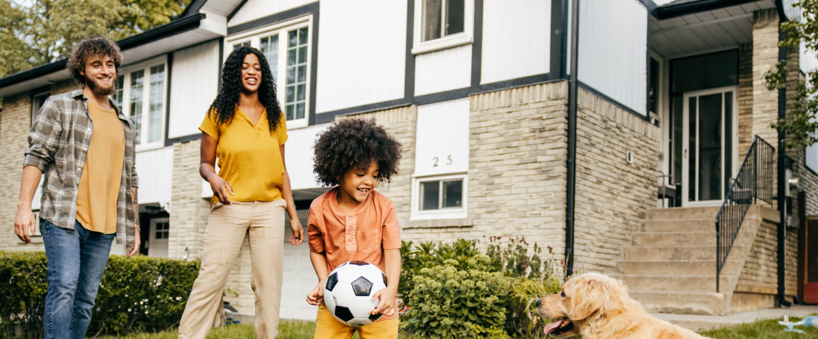 Young family playing outside in front of a house